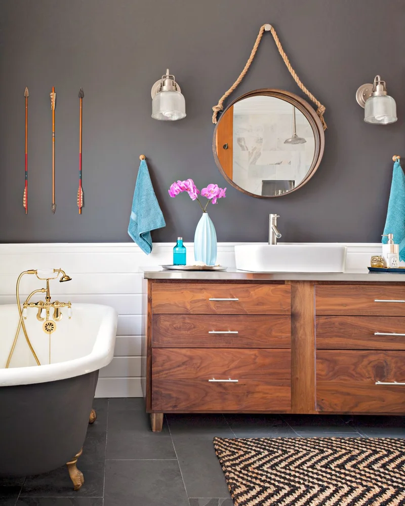 Banheiro pequeno e simples com acessórios pretos e um espelho redondo.