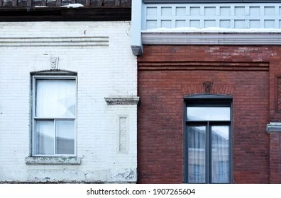 Duas casas geminadas simétricas, compartilhando a parede central e o telhado.