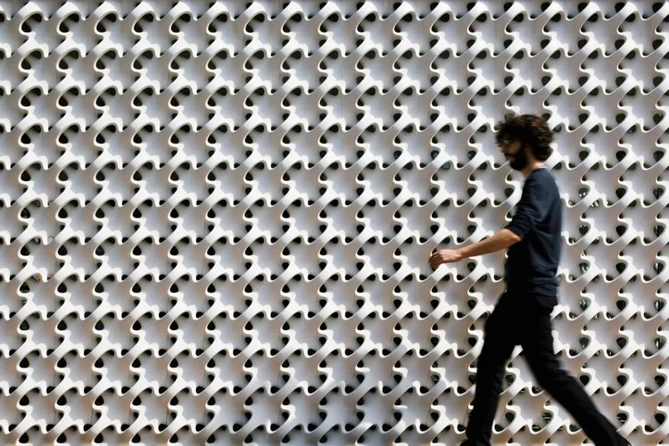 Fachada de um edifício moderno com uma trama de cobogós brancos, criando um padrão de luz e sombra.