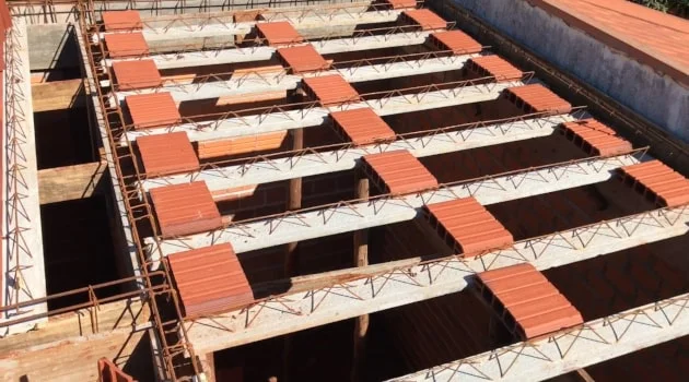 Operários trabalhando na concretagem de uma laje treliçada em uma obra residencial.