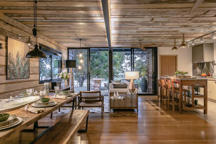 Interior de uma casa contêiner moderna, com paredes brancas, piso de madeira e grandes janelas que permitem a entrada de luz natural, mostrando a amplitude do espaço.