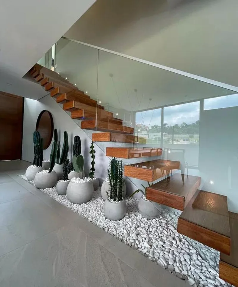 Jardim de inverno elegante sob uma escada com iluminação embutida.