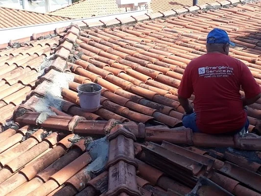 Profissional realizando a manutenção de um telhado, inspecionando a linha da cumeeira.