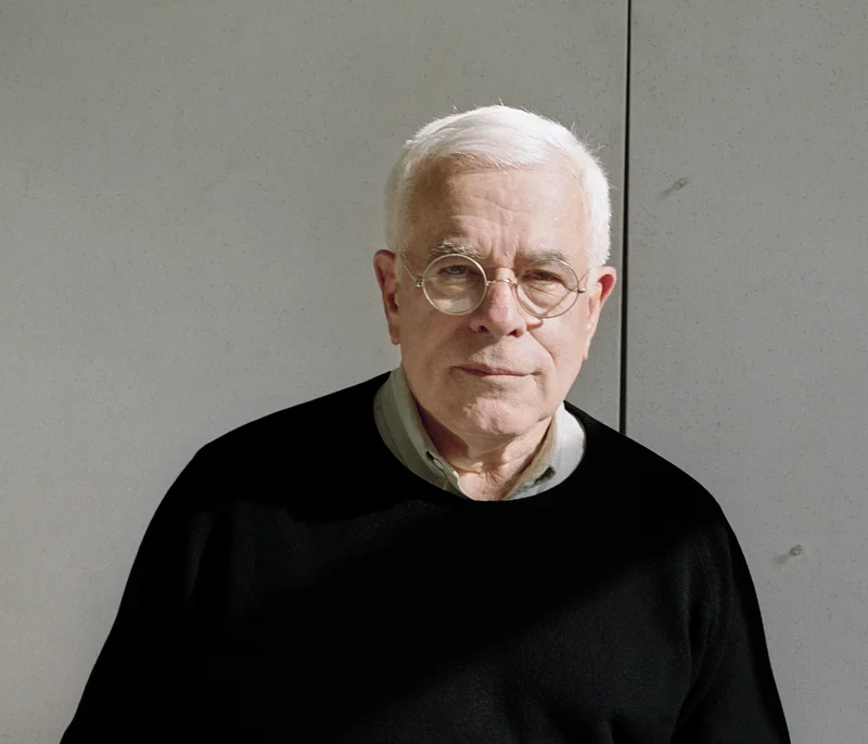 Retrato de Peter Eisenman em seu escritório, cercado por maquetes e livros de arquitetura, transmitindo uma aura de intelectualidade e criatividade.